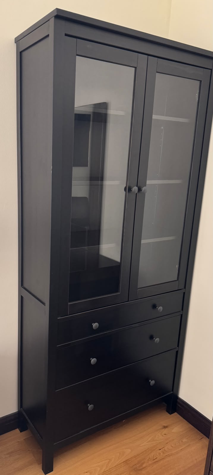 Tall dark wood display cabinet with glass doors and three drawers