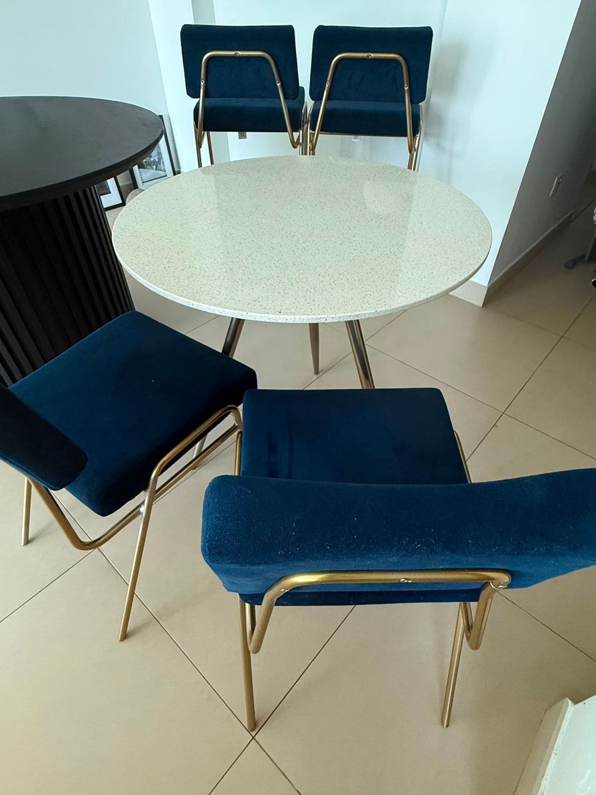Round white terrazzo dining table with 4 navy blue velvet and gold chairs
