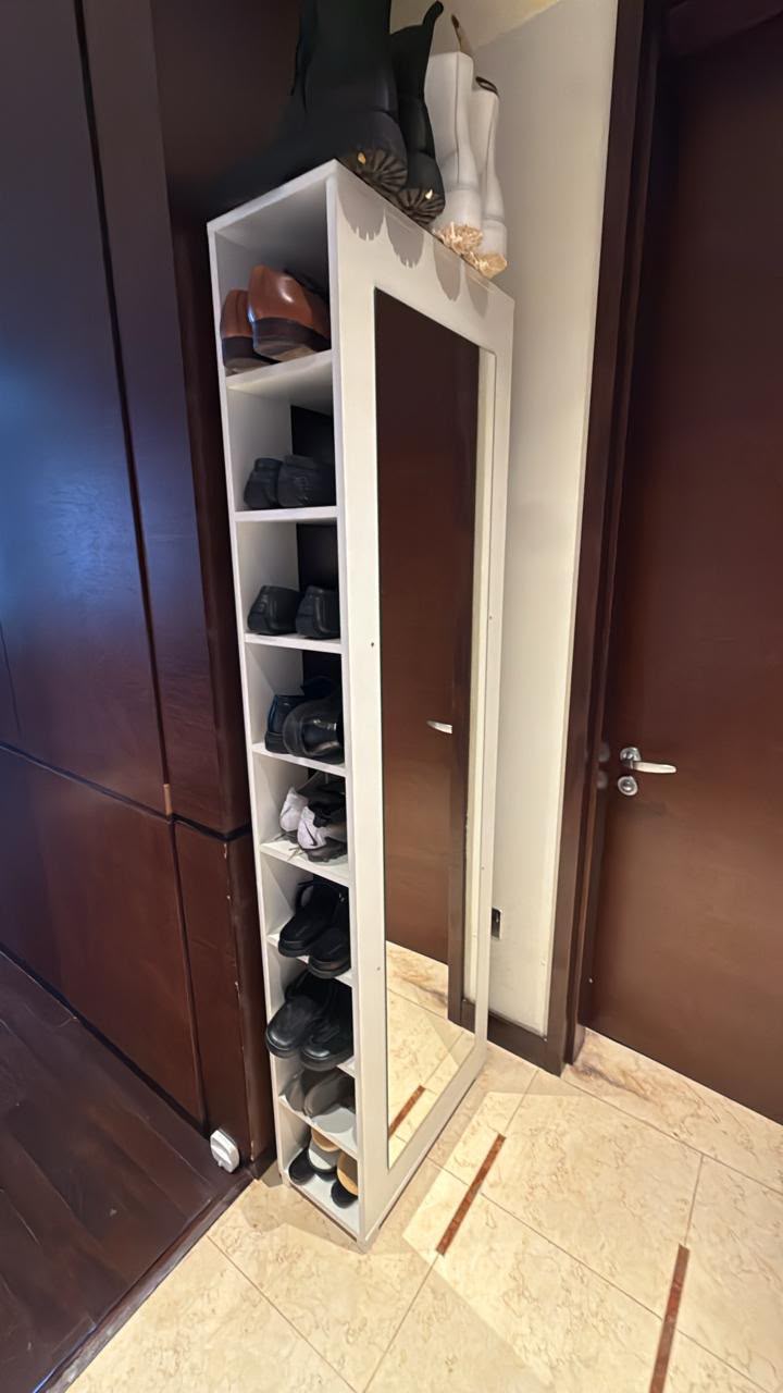 Slim white shoe cabinet with a full-length mirrored door and multiple shelves