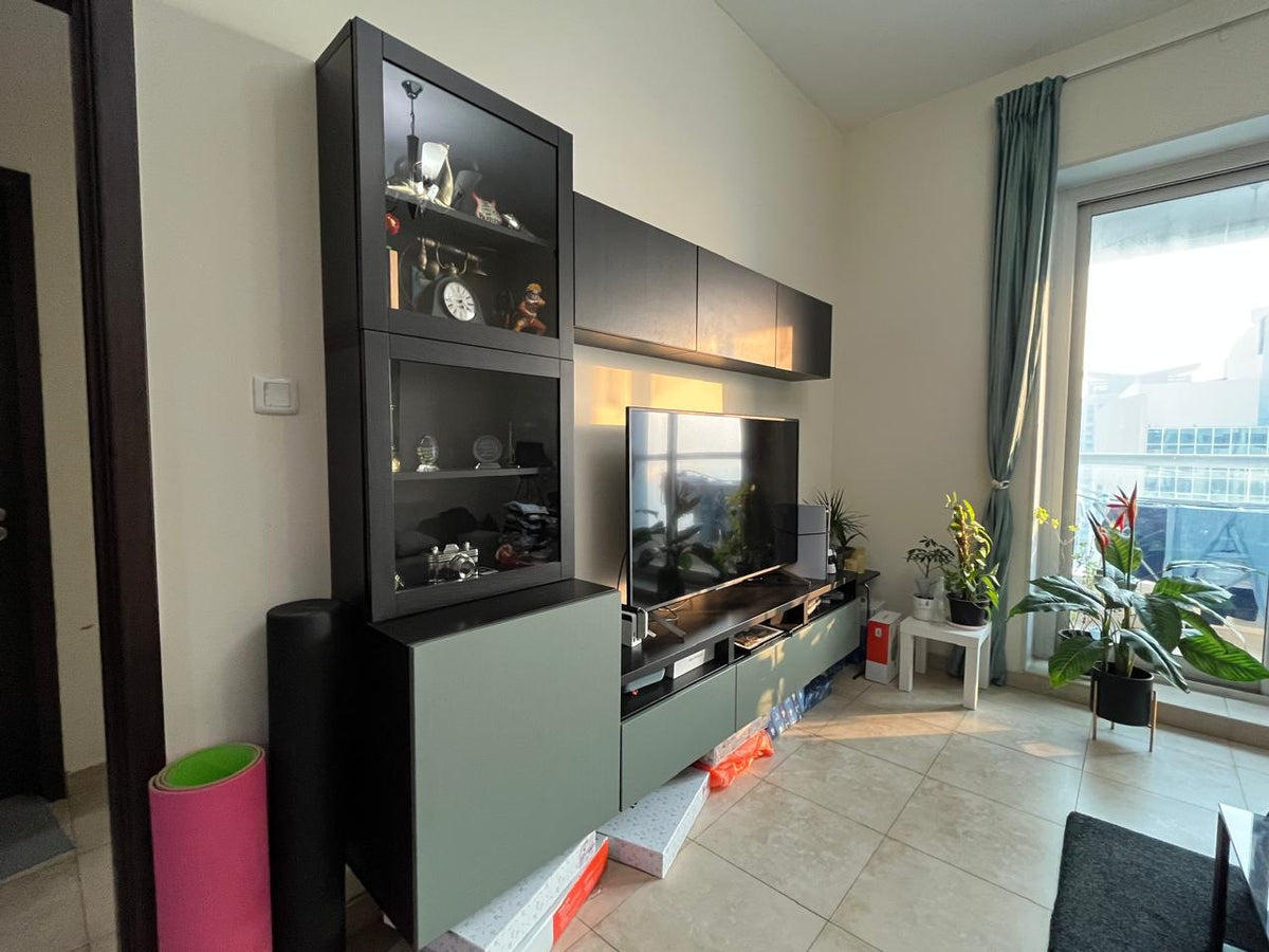 Dark entertainment unit with glass-front display cabinet, TV console and overhead cabinets in living room