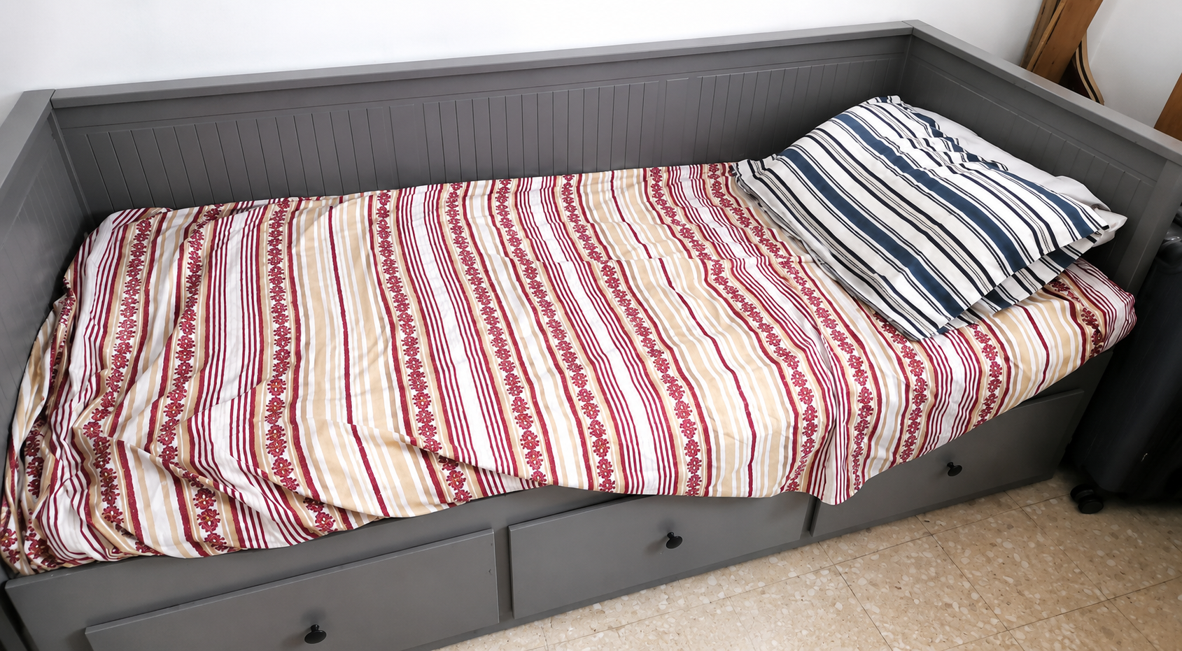 Grey single day bed with 3 storage drawers and striped bedding