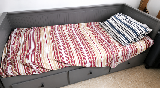 Grey single day bed with 3 storage drawers and striped bedding