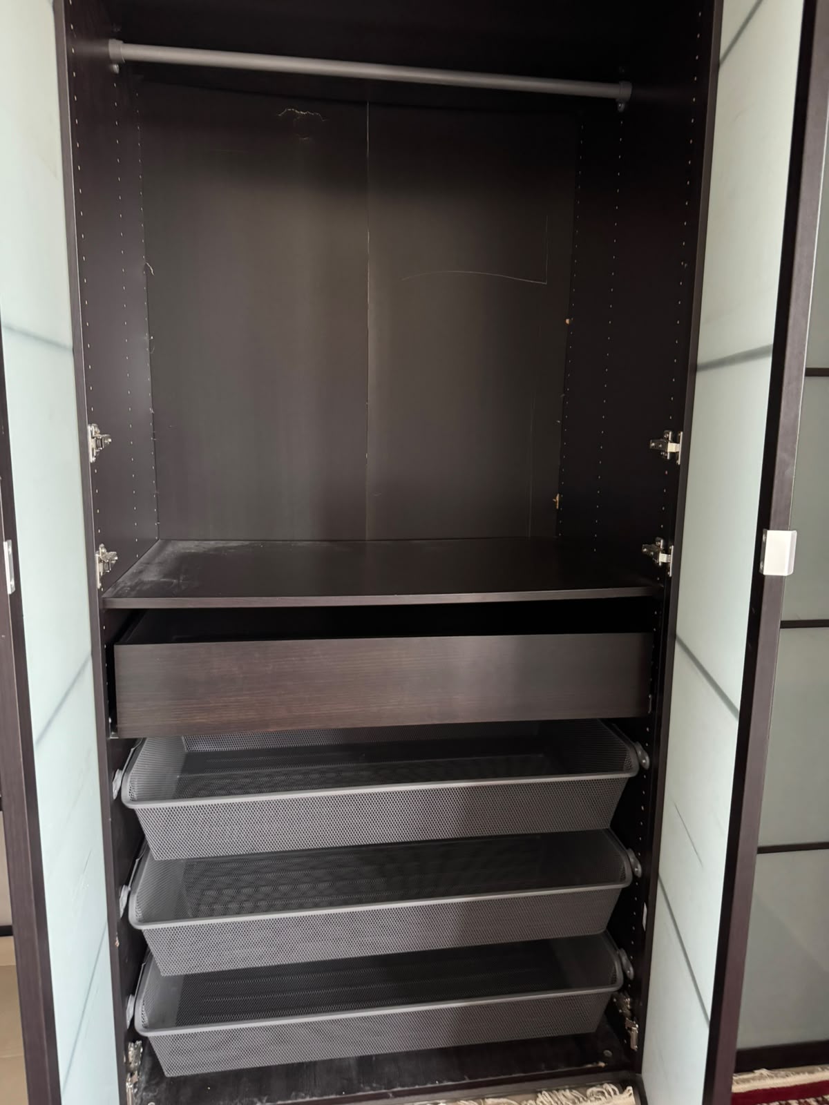 Wardrobe interior showing hanging rail, shelf, and mesh pull-out drawers
