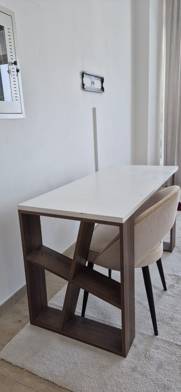 White top dining table with walnut open shelf base, side view with cream chair