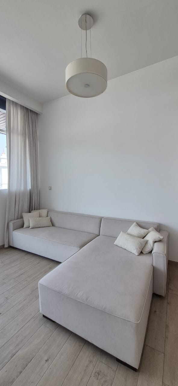 L-shaped sectional sofa in light grey fabric with scatter cushions