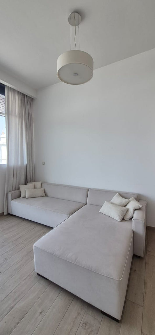 L-shaped sectional sofa in light grey fabric with scatter cushions
