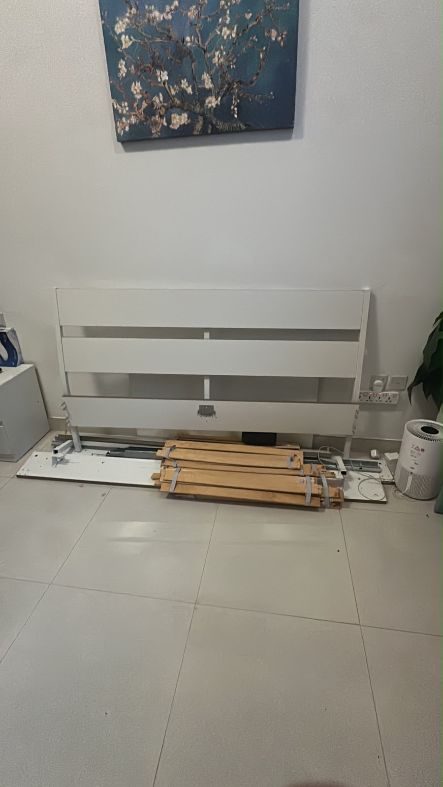 White bed frame disassembled with headboard and wooden slats