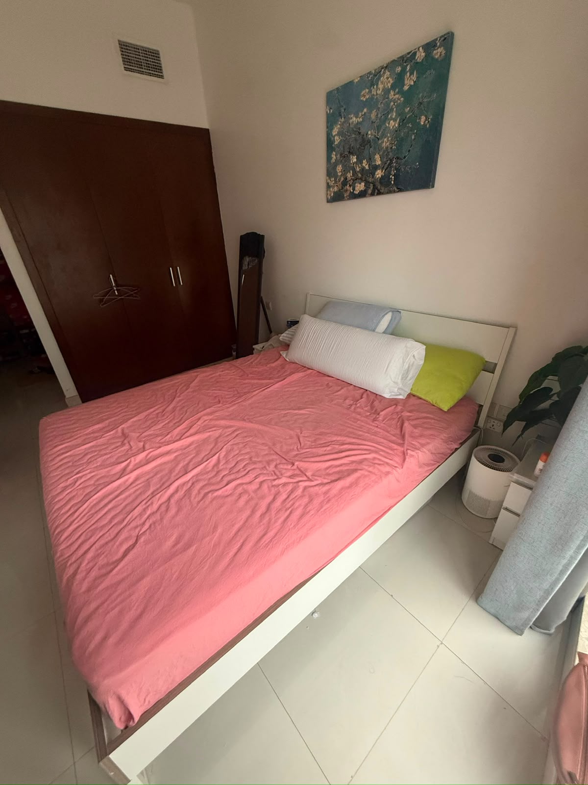 White bed frame fully assembled with pink bedding in bedroom