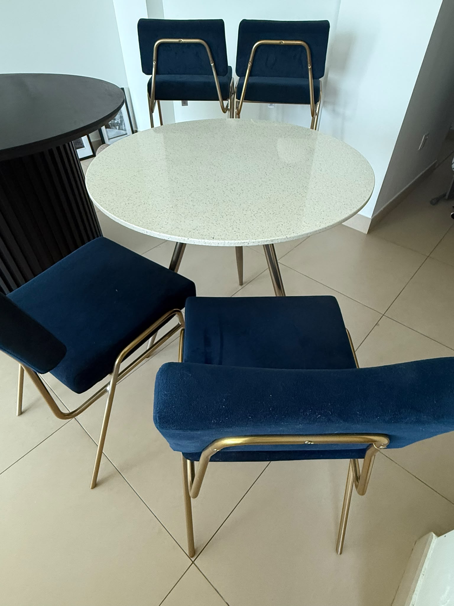 Round white terrazzo dining table with 4 navy blue velvet and gold chairs