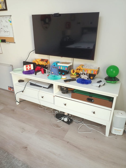 Long white TV unit with drawers and open compartments below wall-mounted television
