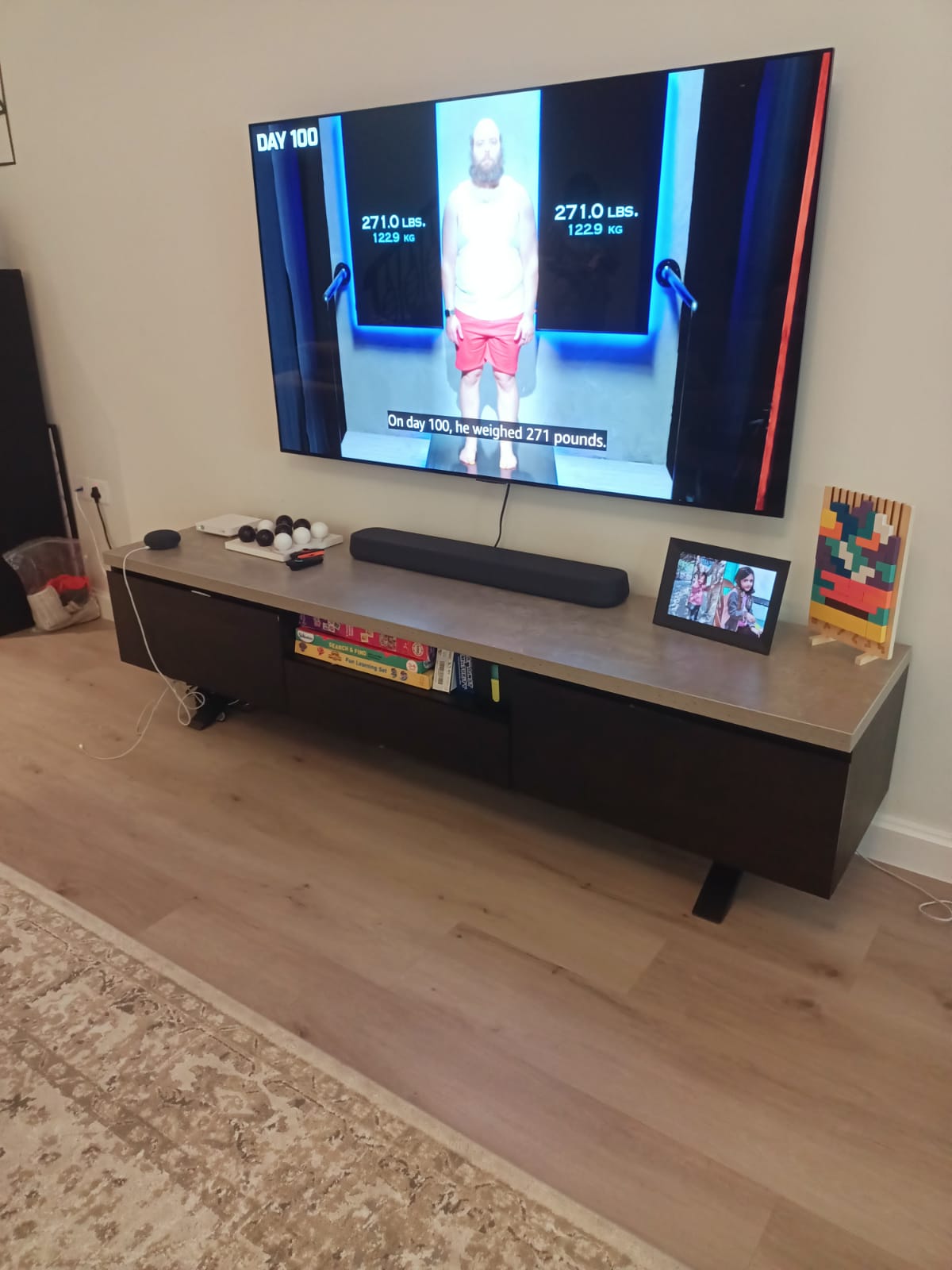 Dark wood TV bench below wall-mounted television