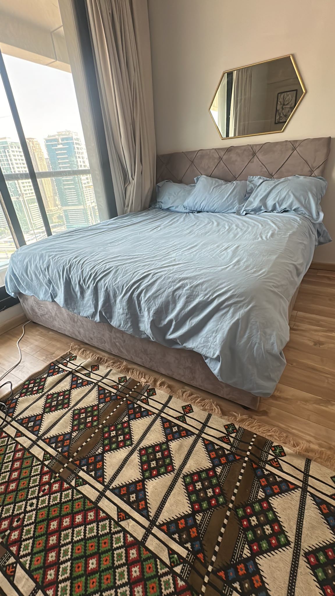 Grey upholstered bed with diamond-tufted headboard in a bedroom