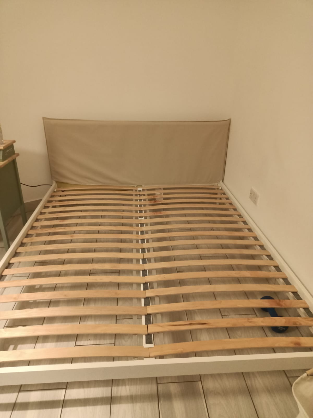 Beige upholstered bed frame with wooden slats and a light-coloured frame