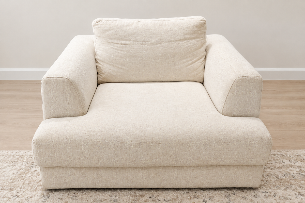 Cleaned-up image of wide cream upholstered lounge chair with broad arms