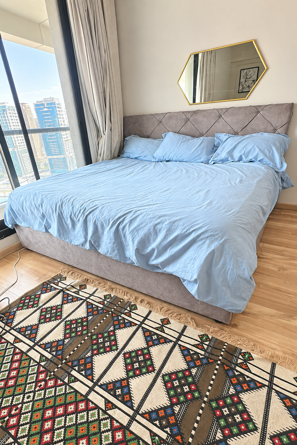 Brightened view of the grey upholstered bed with diamond-tufted headboard
